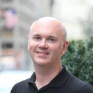 a caucasian man wearing a black shirt smiling at the camera