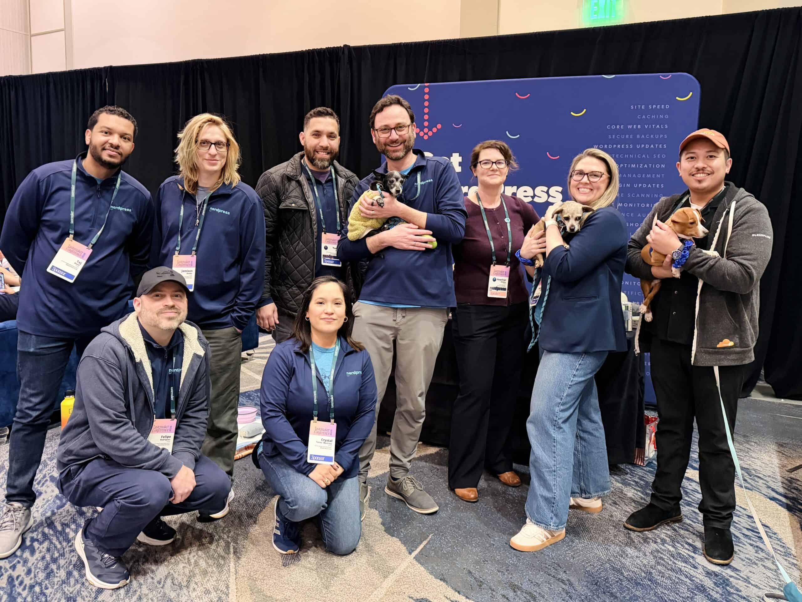 The NerdPress team posing for a group photo at the Tastemaker Conference, holding three very adorable, adoptable dogs.